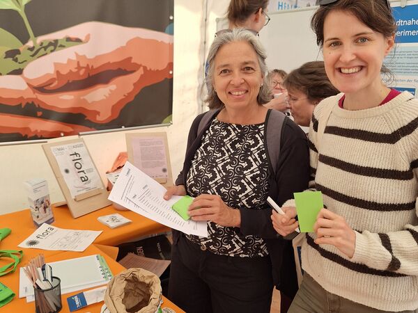 Besucherinnen beim Abfüllen von Saatgut im EMPOWER-Zelt