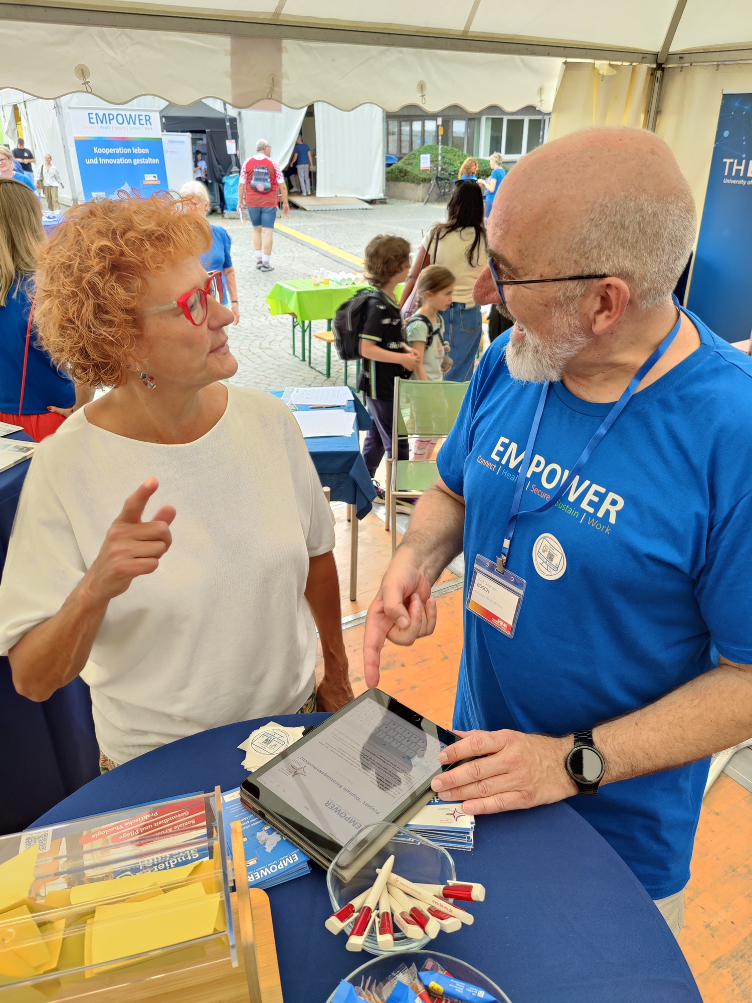 Besucherin im Gespräch mit EMPOWER-Mitarbeiter im Zelt beim Wissenschaftsmarkt (Bild: EMPOWER/Enders)