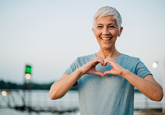 Forschung zum Megatrend Gesundheit: Eine Frau lächelt in die Kamera und formt mit Ihren Händen ein Herz.
